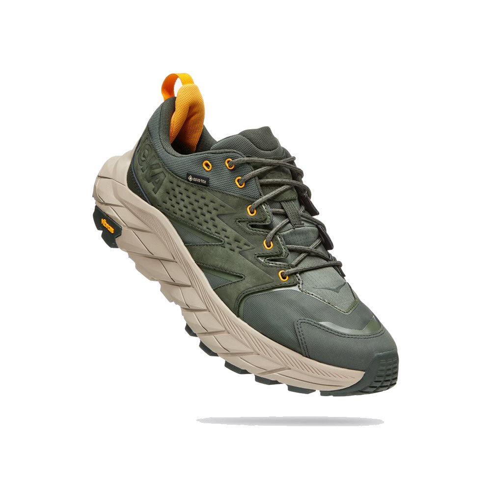 Green Hoka Anacapa Low GTX trail running shoe with rugged sole and orange accents, displayed on a white background.