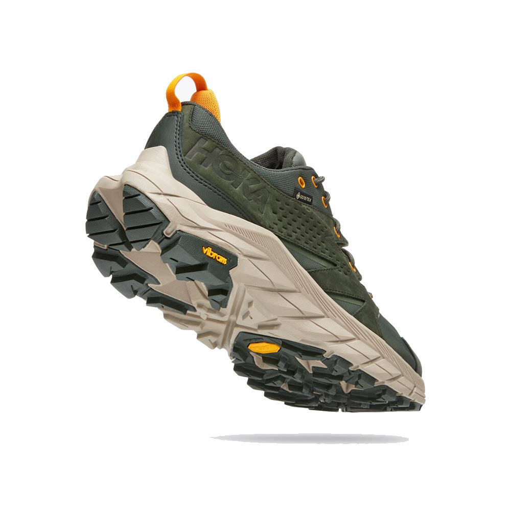 A pair of olive green HOKA ANACAPA LOW GTX hiking shoes with vibram soles and orange detailing, displayed against a white background.