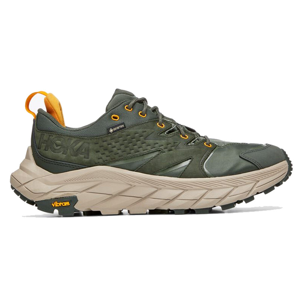Green and gray HOKA ANACAPA LOW GTX hiking shoe with a vibram sole and a yellow loop at the heel, featuring the Hoka brand logo.