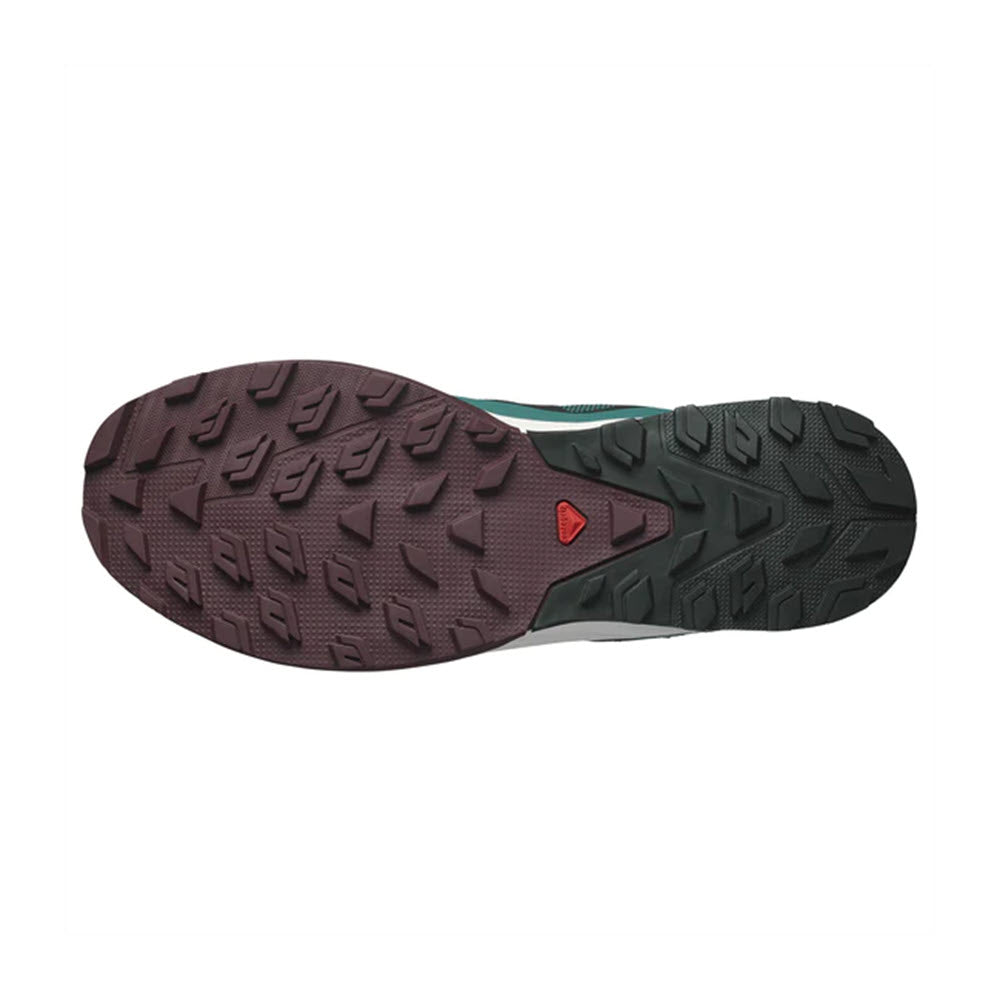 Sole of a Salomon OUTRISE hiking shoe showing deep tread pattern and a red triangular logo on a green background.