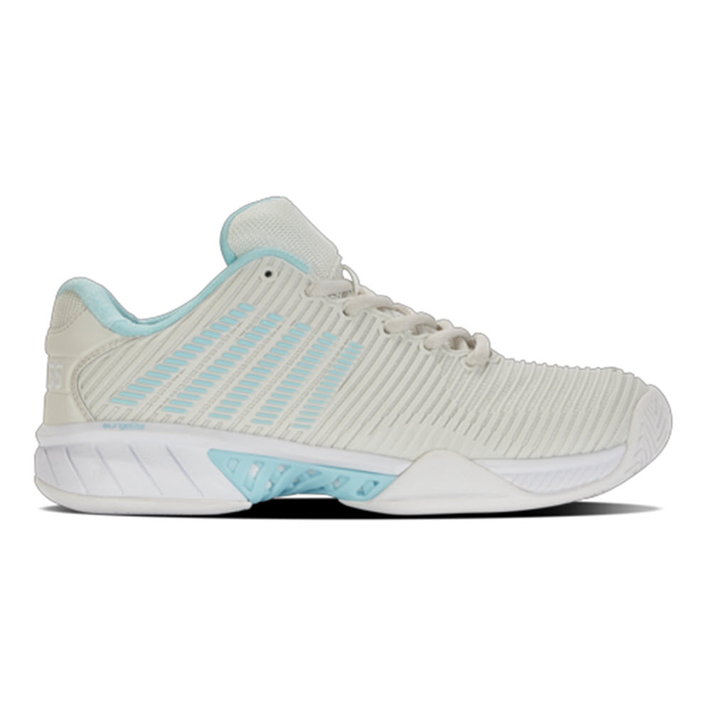 A light gray K-Swiss tennis shoe with pale blue accents featuring a grooved sole and enhanced heel cushioning, now incorporating Surgelite midsole technology.