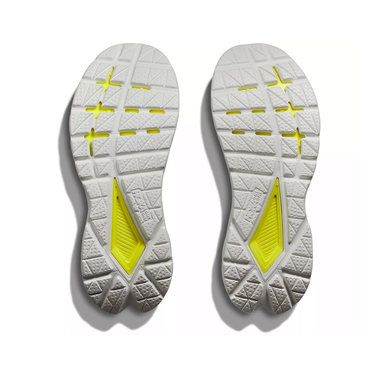 Pair of Hoka running shoes showing white treads and yellow PROFLY midsole elements, isolated on a white background.