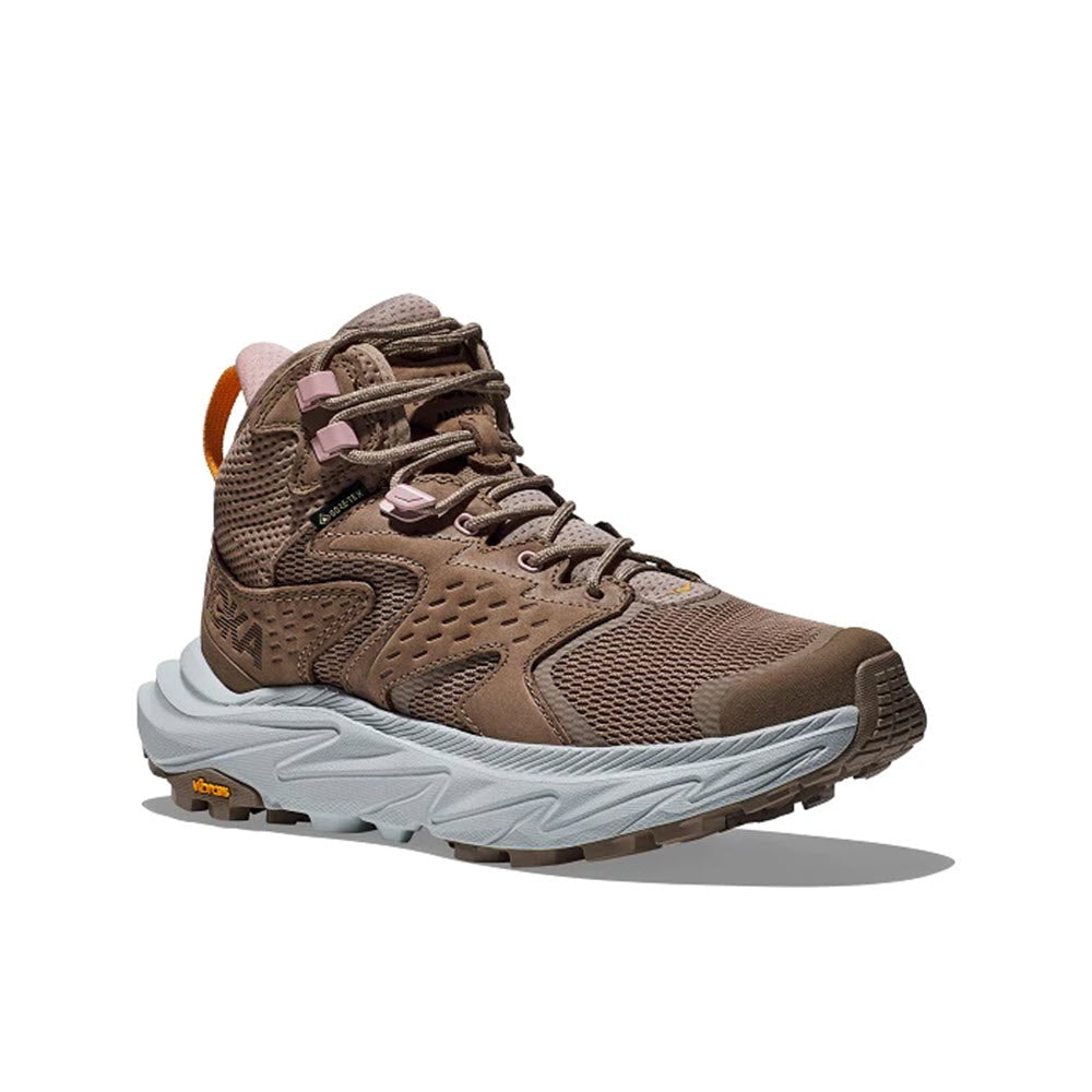 A brown Hoka hiking boot with a chunky gray sole and pink accents, featuring a ventilated upper, displayed on a white background.