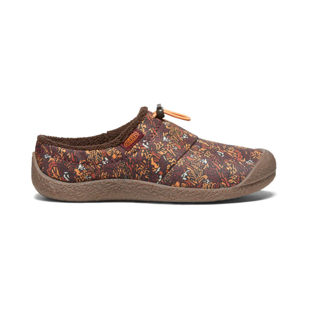 A side view of the KEEN HOWSER III SLIDE ANDORRA CAMO - WOMENS with a brown sole and a multicolored, patterned fabric upper. The shoe features a small orange Keen logo on the side, an adjustable bungee toggle at the top, and offers hybrid comfort slide design for improved traction.