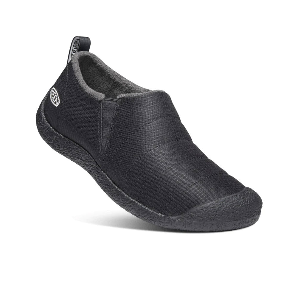 A single KEEN HOWSER II SLIPPER TRIPLE BLACK - MENS with a fleece lining, a textured upper, and a curved, ergonomic sole, displayed against a white background.