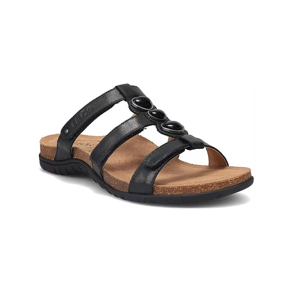 A Taos Gemma Black sandal with a Cork Support™ footbed and three circular Tiger Eye stone embellishments on the straps, displayed against a white background.