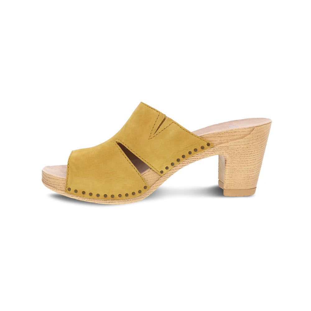A Dansko mustard yellow women&#39;s Tandi sandal with a chunky wooden heel, featuring cut-out details and decorative studs, isolated on a white background.