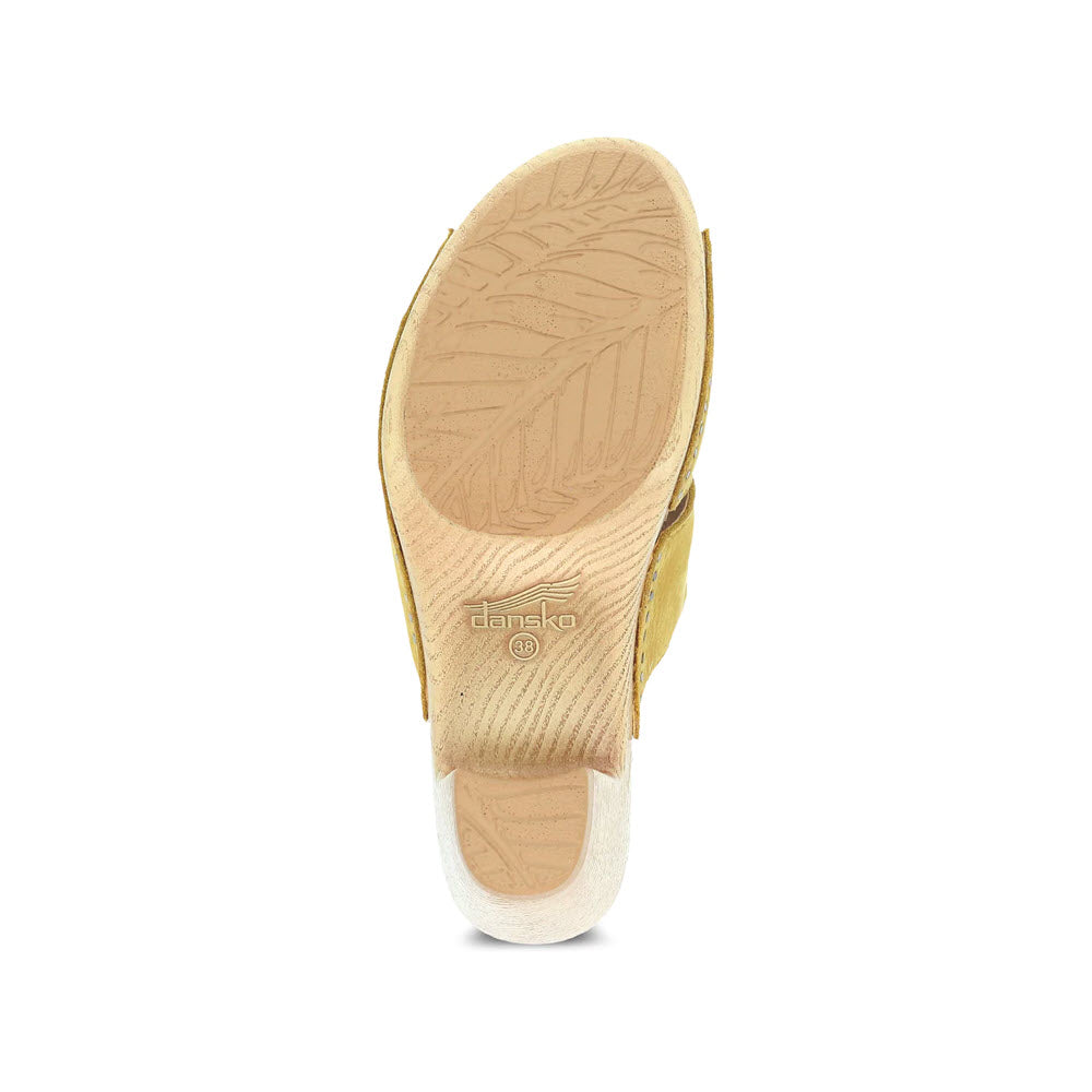 Top view of a single beige Dansko Tandi sandal with leaf pattern on the sole, displayed against a white background.