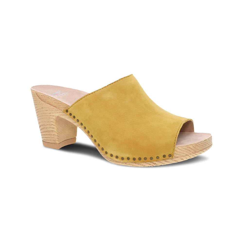 A Dansko Tandi Yellow women&#39;s mule shoe with soft leather uppers, a chunky wooden heel, and studded details around the edge, displayed against a white background.