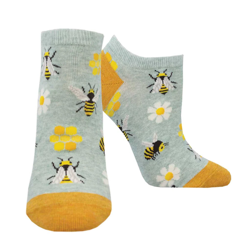A pair of SOCKSMITH TO BE OR NOT TO BE PED SOCKS MINT - WOMENS in light gray, featuring a pattern of yellow bees and white daisies, with yellow toe and heel patches.