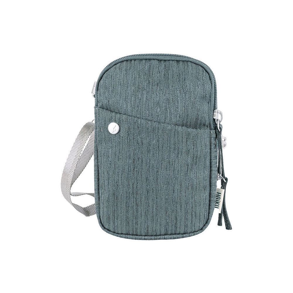 A small denim Haiku Endeavour pouch deep forest with a front flap, snap closure, and adjustable straps, isolated on a white background.