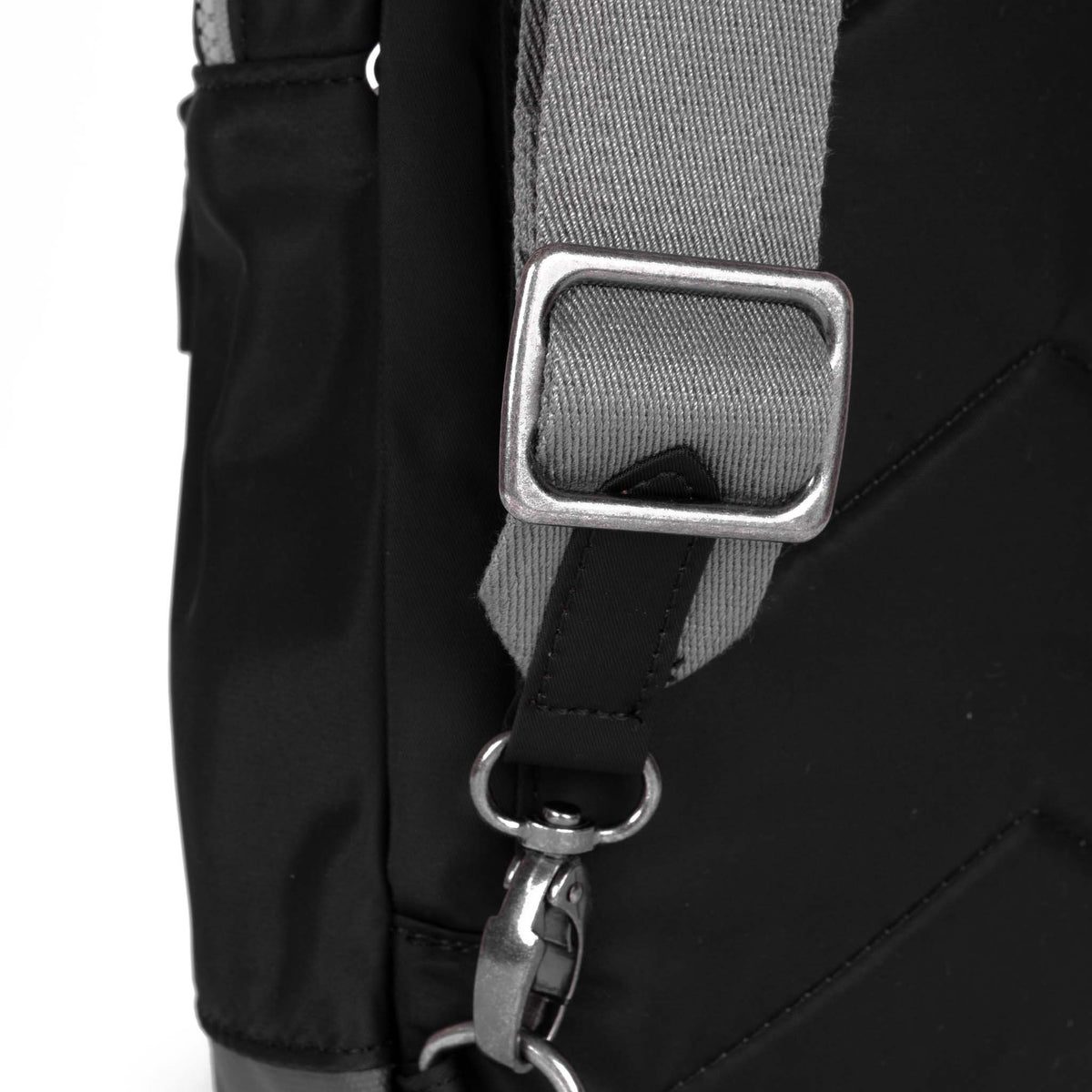 Close-up of a black strap with a metal buckle and clip on an Ori London Willlesden B Large Sling Black crossbody bag, emphasizing the texture and hardware details.