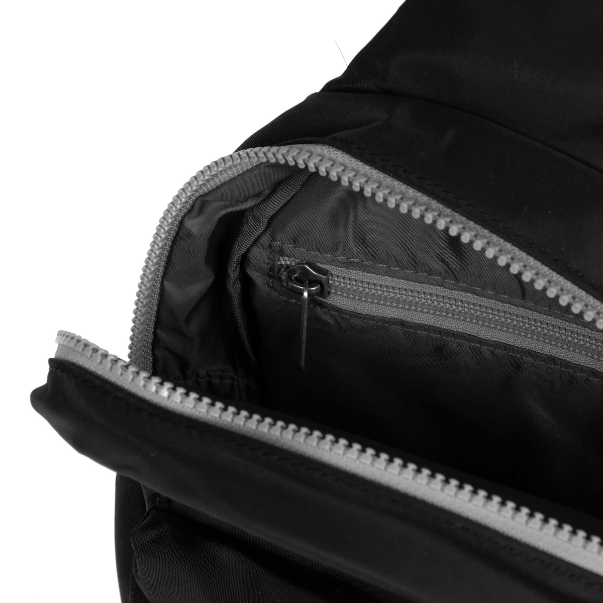 Close-up of a black jacket with an open zipper, showing detailed stitching and the textured fabric of the integrated Ori London Willesden B Large Sling Black made from recycled material.