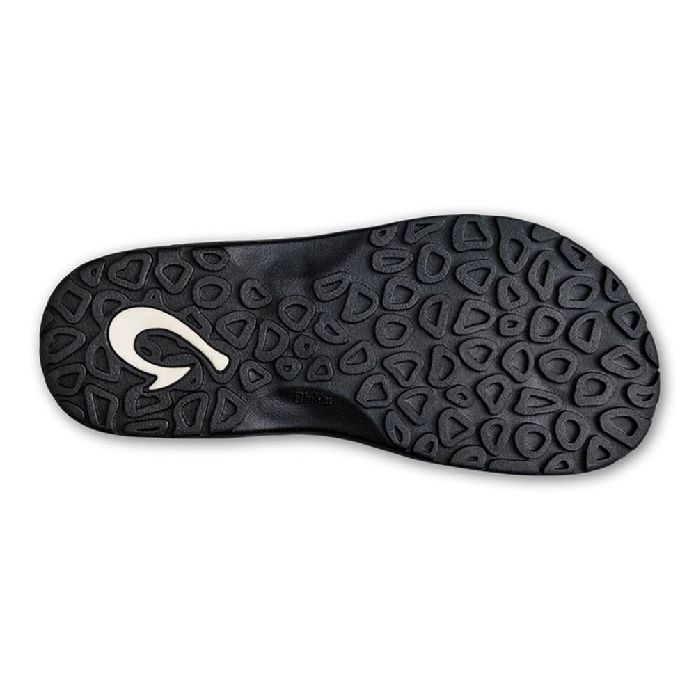 Bottom view of a black Olukai Ohana Flip Flop Navy/Onyx sole featuring a distinctive, embossed tread pattern and a white logo on the heel area.