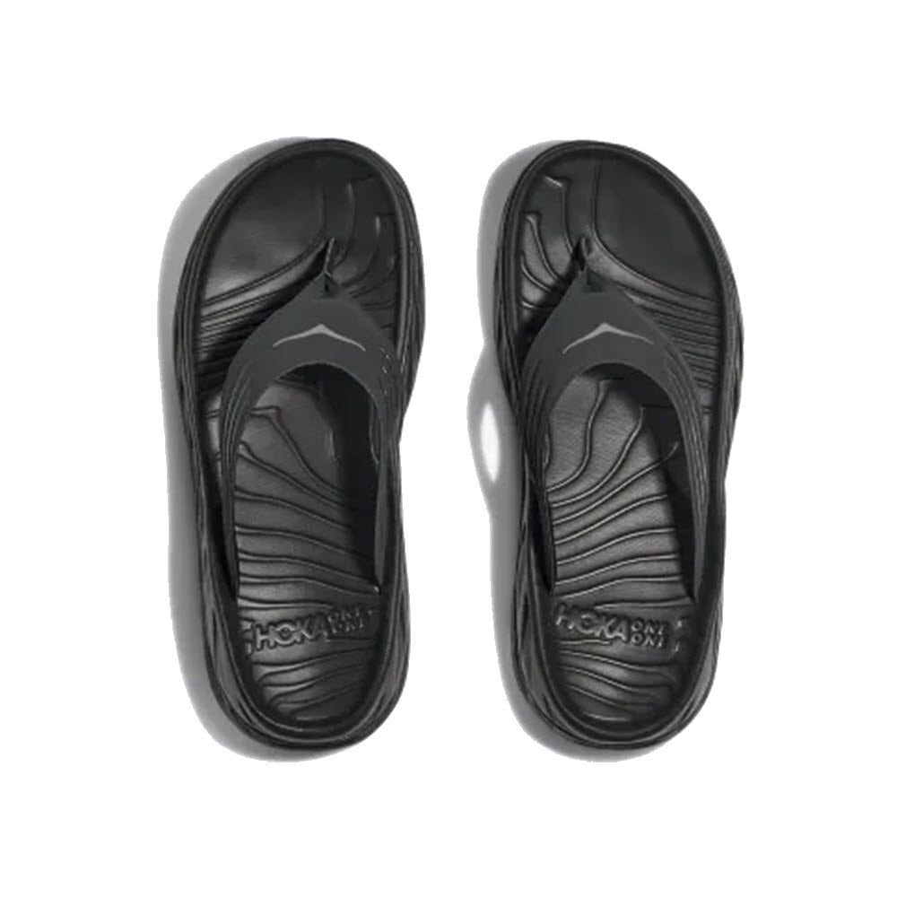 A pair of black HOKA ORA RECOVERY FLIP flip-flops displayed on a white background.