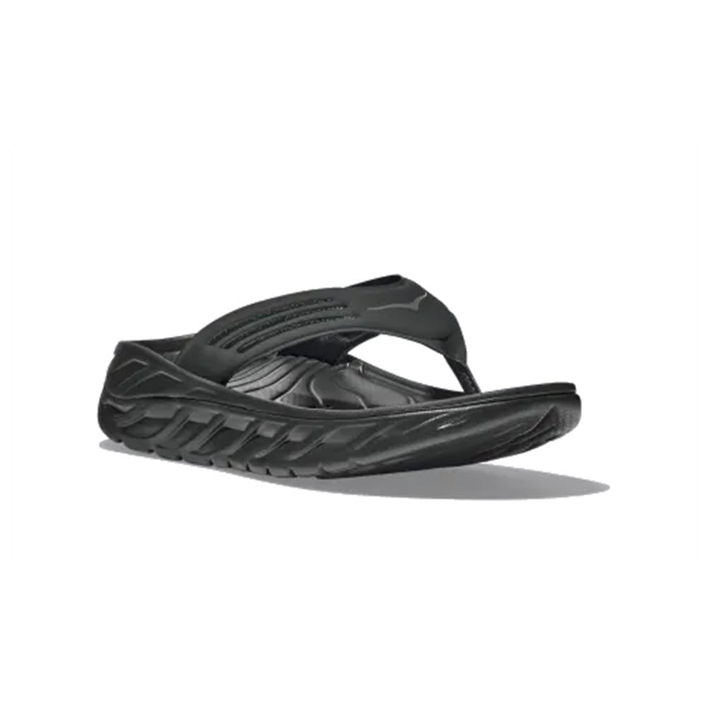 A pair of black Hoka HOKA ORA RECOVERY FLIP flip-flops with thick, textured soles on a white background.