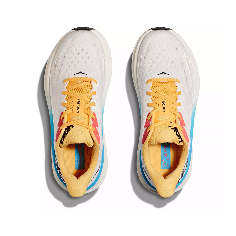Top view of a pair of white Hoka CLIFTON 9 BLANC DE BLANC/SWIM DAY running shoes with yellow laces and colorful accents, isolated on white background.