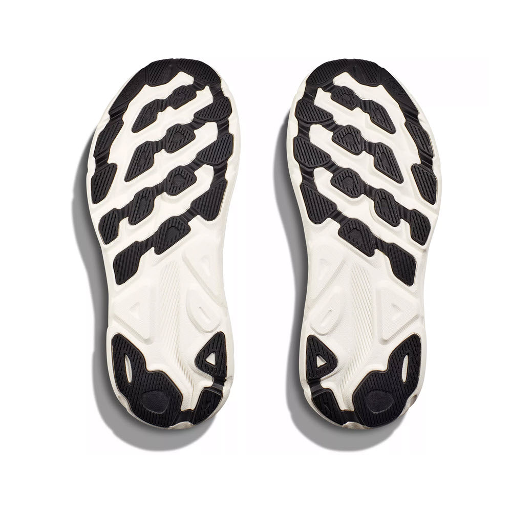 Pair of Hoka sneaker soles with a black and white tread pattern, featuring a breathable engineered mesh, isolated on a white background.