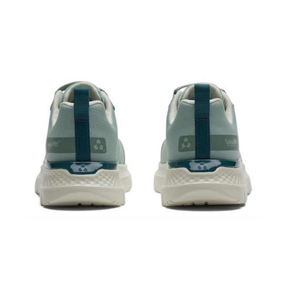 Rear view of a pair of Timberland Steel Toe Intercept Oxford Sage White - Womens safety toe shoes with blue heel loops and white soles, featuring a paw print logo on the heels.