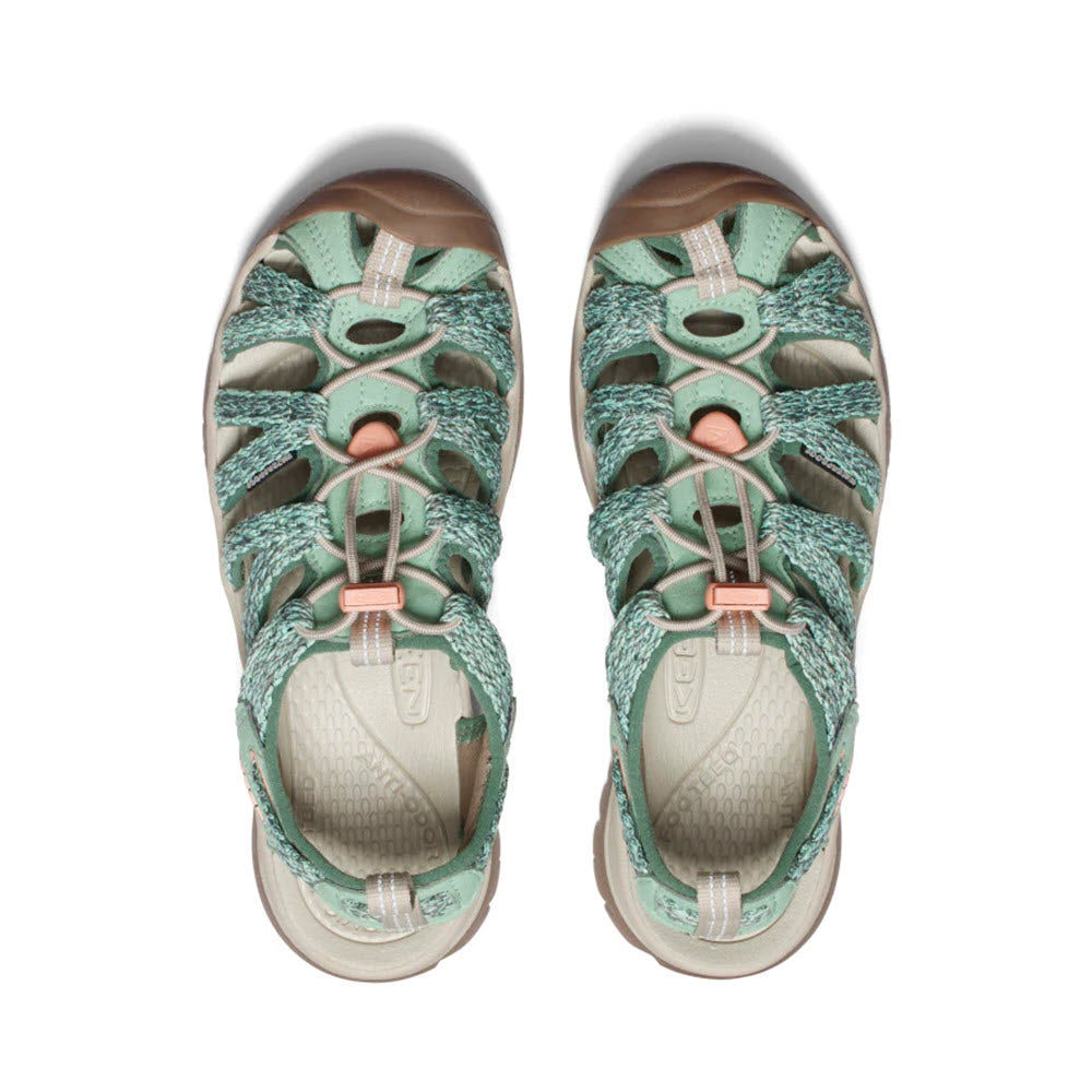 A pair of Keen Whisper Granite Green hiking sandals displayed from a top view, featuring a unique strap design and closed toes.