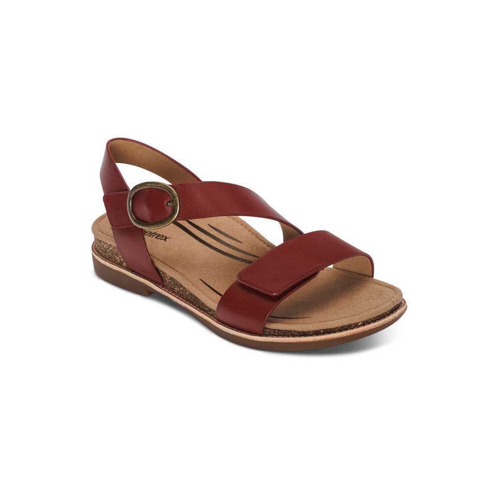 A single Aetrex Tamara Red - Women&#39;s sandal with an ankle strap and a decorative circular buckle, displayed against a white background, featuring a genuine leather upper.