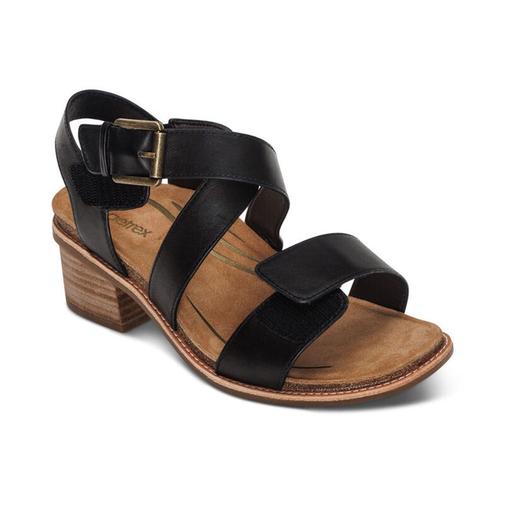 A Aetrex KRISTIN BLACK - WOMENS leather strappy sandal with a chunky brown heel and an adjustable hook and loop closure on a white background.