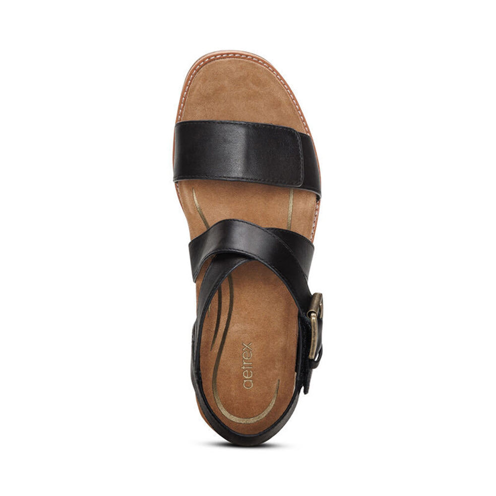 Top view of a single brown and black Aetrex Kristin Black - Womens sandal with straps and an adjustable hook and loop closure against a white background.