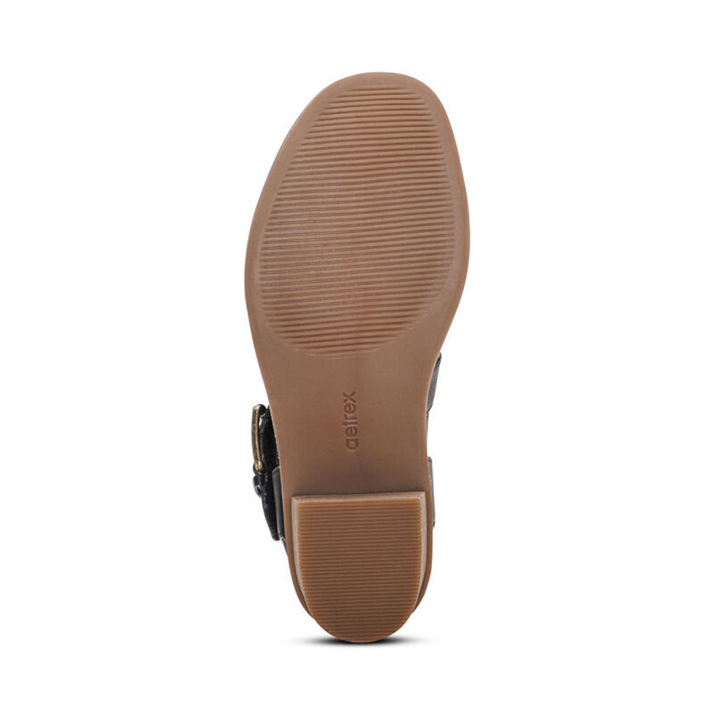 Sole of a brown shoe with textured treads and an adjustable hook and loop closure, embossed with the brand name &quot;Aetrex&quot;.