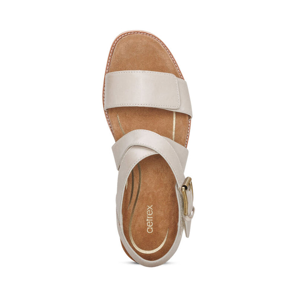 Aetrex Kristin Ivory suede sandal with a white strap across the top, featuring an adjustable hook and loop closure, set against a plain white background.