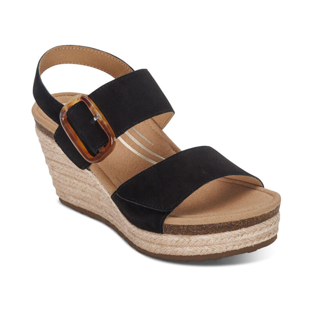 A single Aetrex Ashley Black wedge sandal with a cork platform, suede upper straps, and a large tortoiseshell buckle on a white background. This sandal features a memory foam footbed for added comfort.