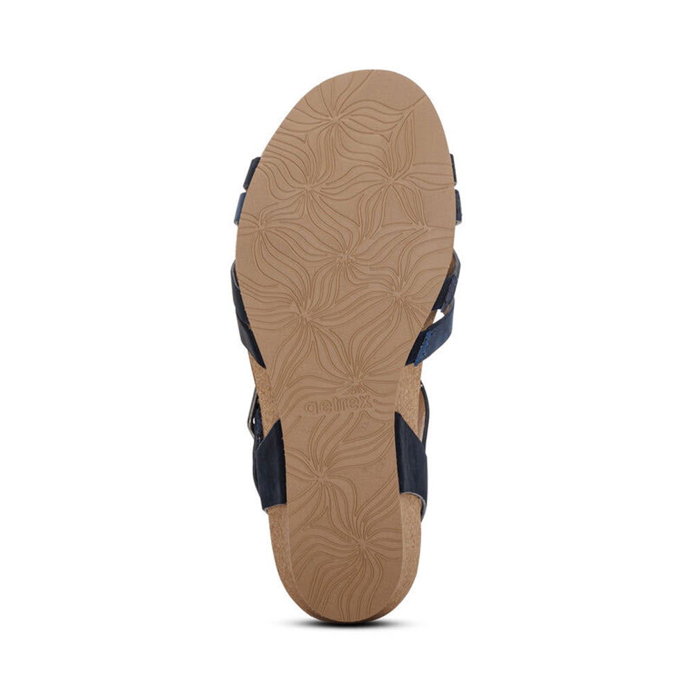 Single sandal with a detailed floral-patterned sole and navy straps featuring adjustable hook &amp; loop closure, viewed from the bottom against a white background. The product is the AETREX NOELLE NAVY - WOMENS by Aetrex.