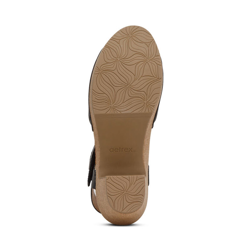 Bottom view of a beige Aetrex Finley Black - Womens shoe showing its textured sole with a floral design, arch support, and the Aetrex logo embossed in the middle.