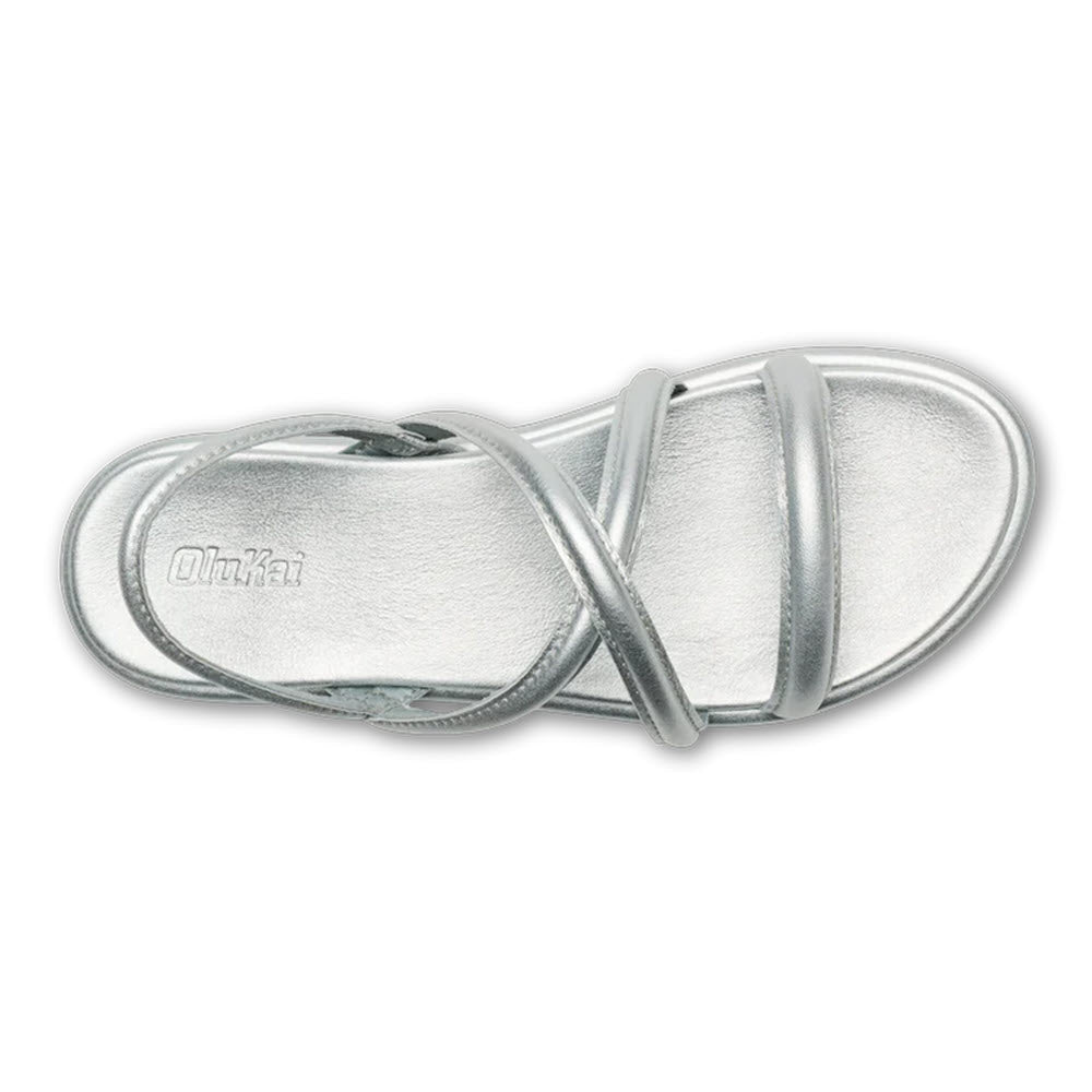 A pair of metallic silver Olukai Tiare Strappy slide sandals with a single broad strap over the foot, displayed on a white background.