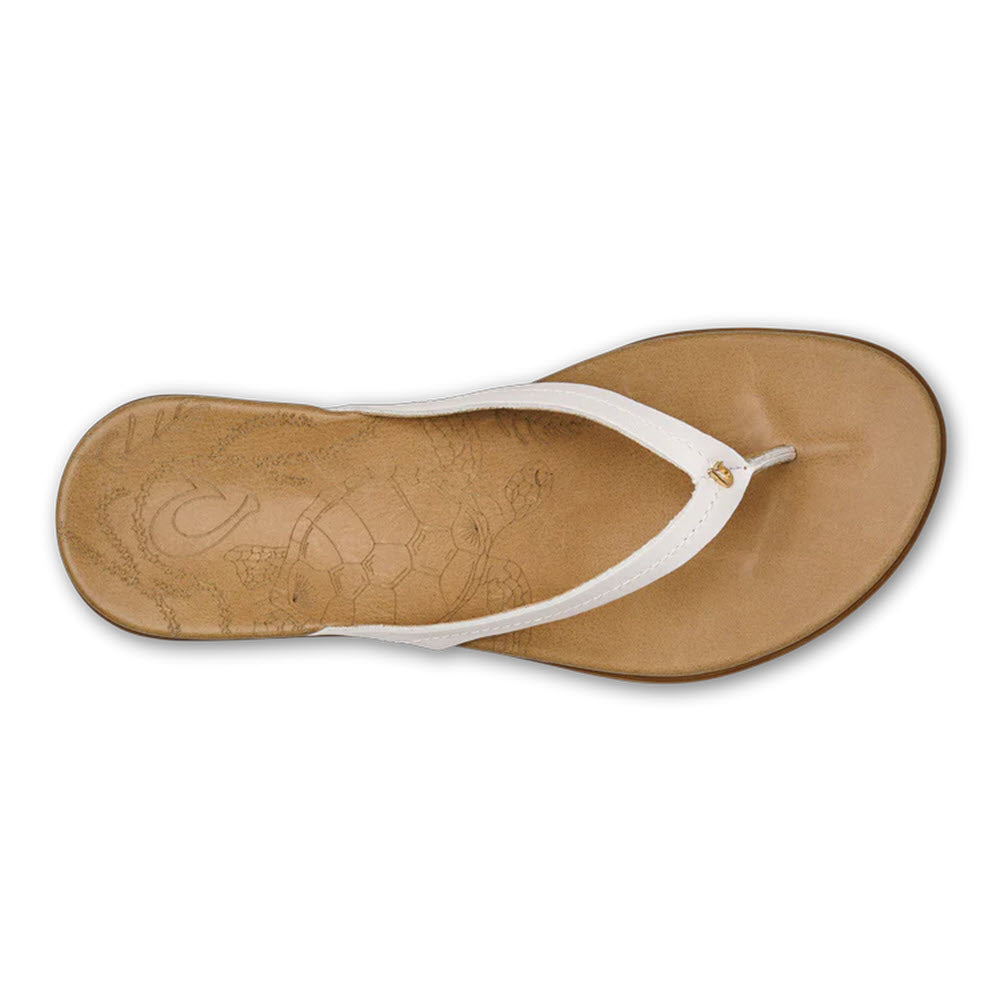 Top view of a single Olukai Honu Bright White - Womens flip-flop with a leather footbed featuring a Hawaiian Green Sea Turtle pattern imprint.