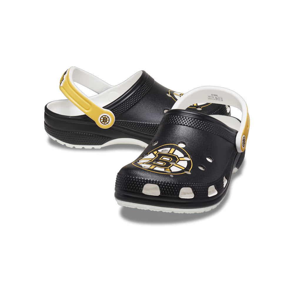 A pair of black and yellow Crocs Boston Bruins Classic Clog White - Mens with the team logo on the adjustable straps, displayed against a white background.