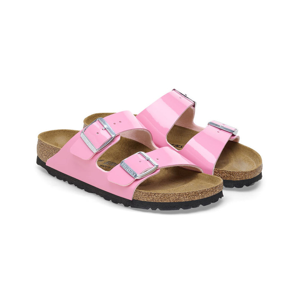 A pair of pink Birkenstock Arizona sandals with adjustable straps and cork soles on a white background.