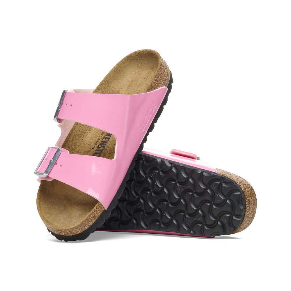 A pair of pink Birkenstock Arizona sandals with adjustable straps, cork footbeds, and black soles isolated on a white background.