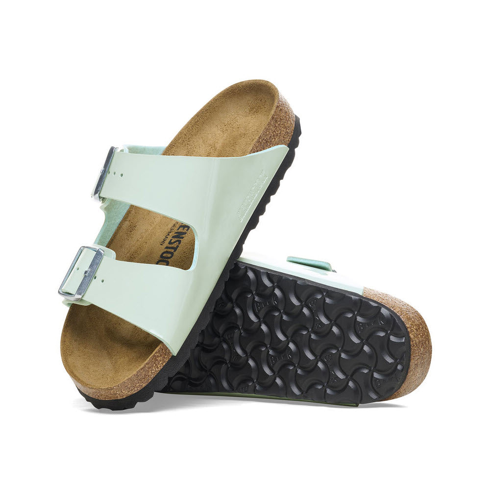 Mint green Birkenstock Arizona sandal with an adjustable strap and buckle, featuring a cork footbed and black sole, displayed against a white background.