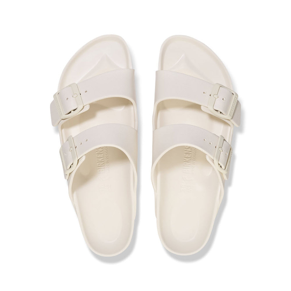 A pair of white Birkenstock Arizona slide sandals with adjustable straps, viewed from above on a white background.
