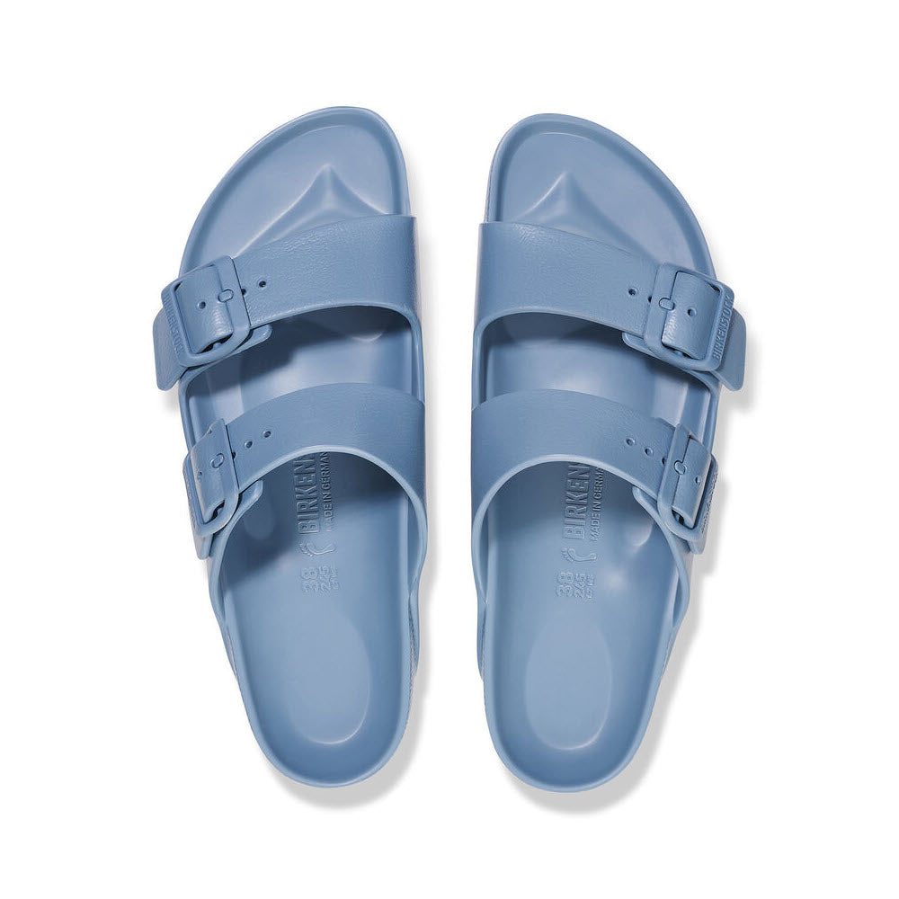A pair of light blue Birkenstock Arizona EVA Elemental Blue - Womens sandals with adjustable straps, positioned symmetrically on a white background.