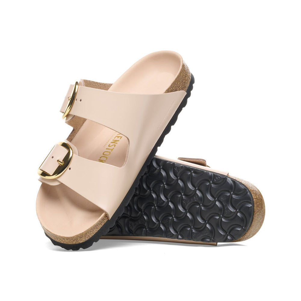 A pair of beige Birkenstock Arizona Big Buckle sandals with a single strap, gold buckle, and black textured soles, positioned against a white background.