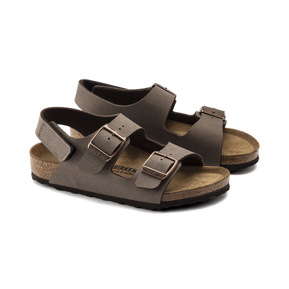 A pair of brown Birkenstock Milano Hook &amp; Loop Mocha Birkibuc sandals with adjustable straps and metal buckles on a white background.