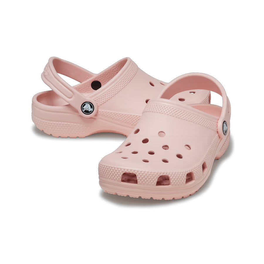 An iconic Crocs Classic Clog Quartz in light pink with circular ventilation holes and a pivoting heel strap, isolated on a white background.