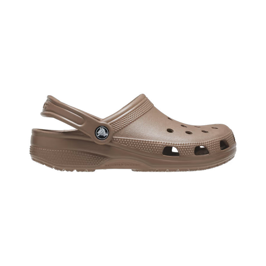 An iconic Crocs Classic Clog Latte featuring a single brown rubber design with ventilation holes and a pivoting heel strap, isolated on a white background.