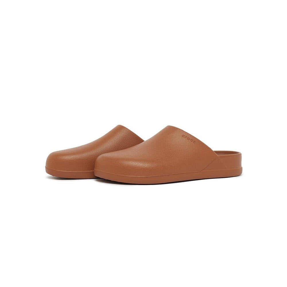 Pair of CROCS DYLAN CLOG COGNAC slip-on shoes crafted with Iconic Crocs Comfort™ on a white background.