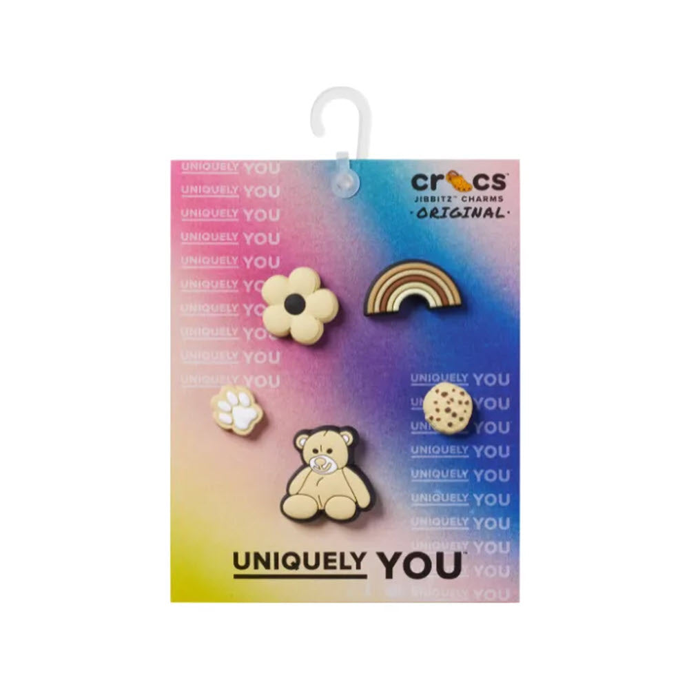 A package of Crocs Jibbitz charms, featuring designs of a flower, rainbow, bear, and cookie, displayed on a colorful &quot;uniquely you&quot; card inspired by pop culture.