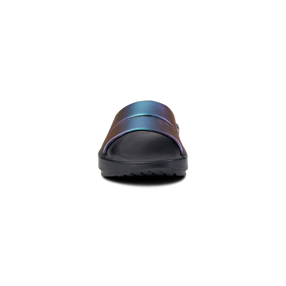 A single iridescent slide sandal with a streamlined footbed and a black sole, viewed from the front on a white background. - OOFOS OOAHH LUXE MIDNIGHT SPECTRE slide sandal by Oofos