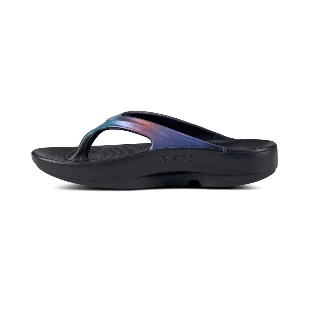 A single black Oofos OOlala Luxe Midnight Spectre sandal with a shiny, iridescent strap, displayed on a white background.
