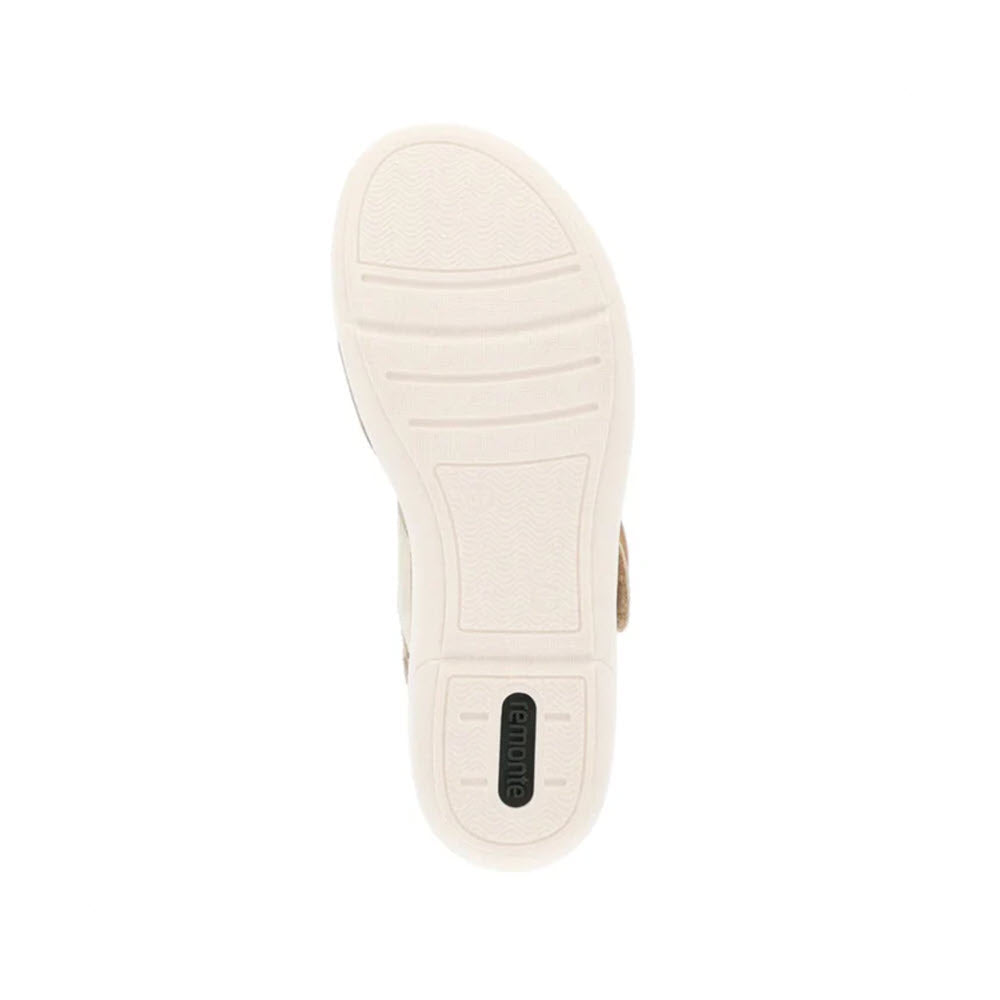 Bottom view of a Remonte Big Buckle Comfort Sandal Light Metallic - Womens showing a beige sole with horizontal grooves and a small rectangular label in the center, featuring an exchangeable footbed.