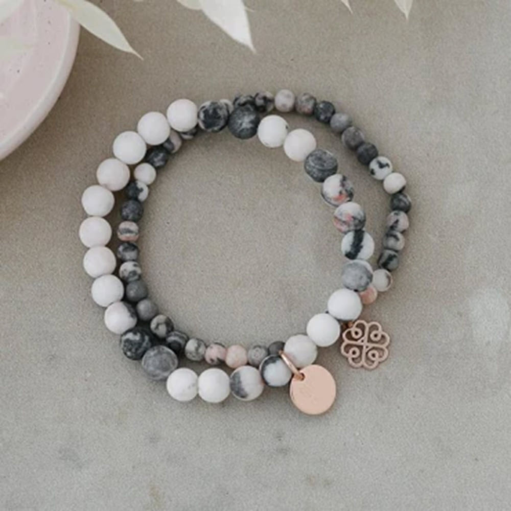 Two GLEE STACK EM UP BRACELETS PINK ZEBRA with white and gray marbled patterns, hypoallergenic and nickel-free, one featuring a rose gold charm.